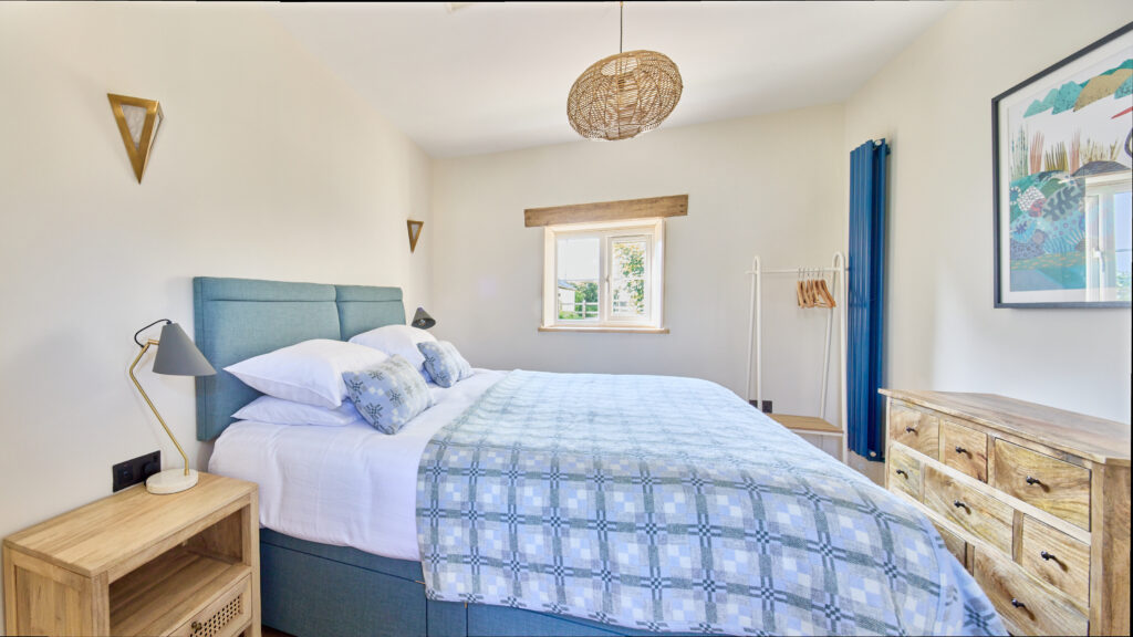 Bedroom of cottage with large bed and blue Welsh wool blanket on bed