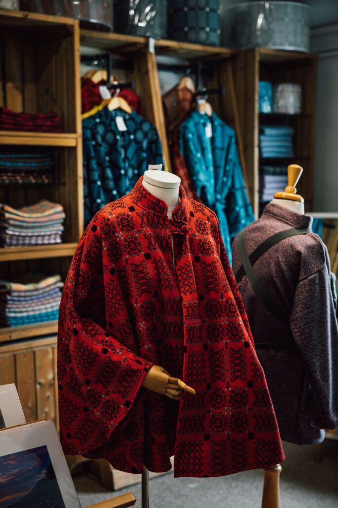 Red Welsh wool blanket cape in Melin Tregwynt shop with blue dressing gowns in the background