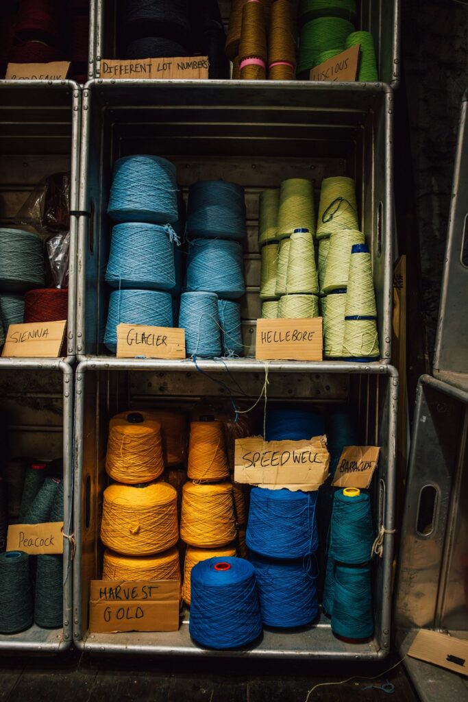 Spools of blue, green, orange wool on shelves with names of colours on cards